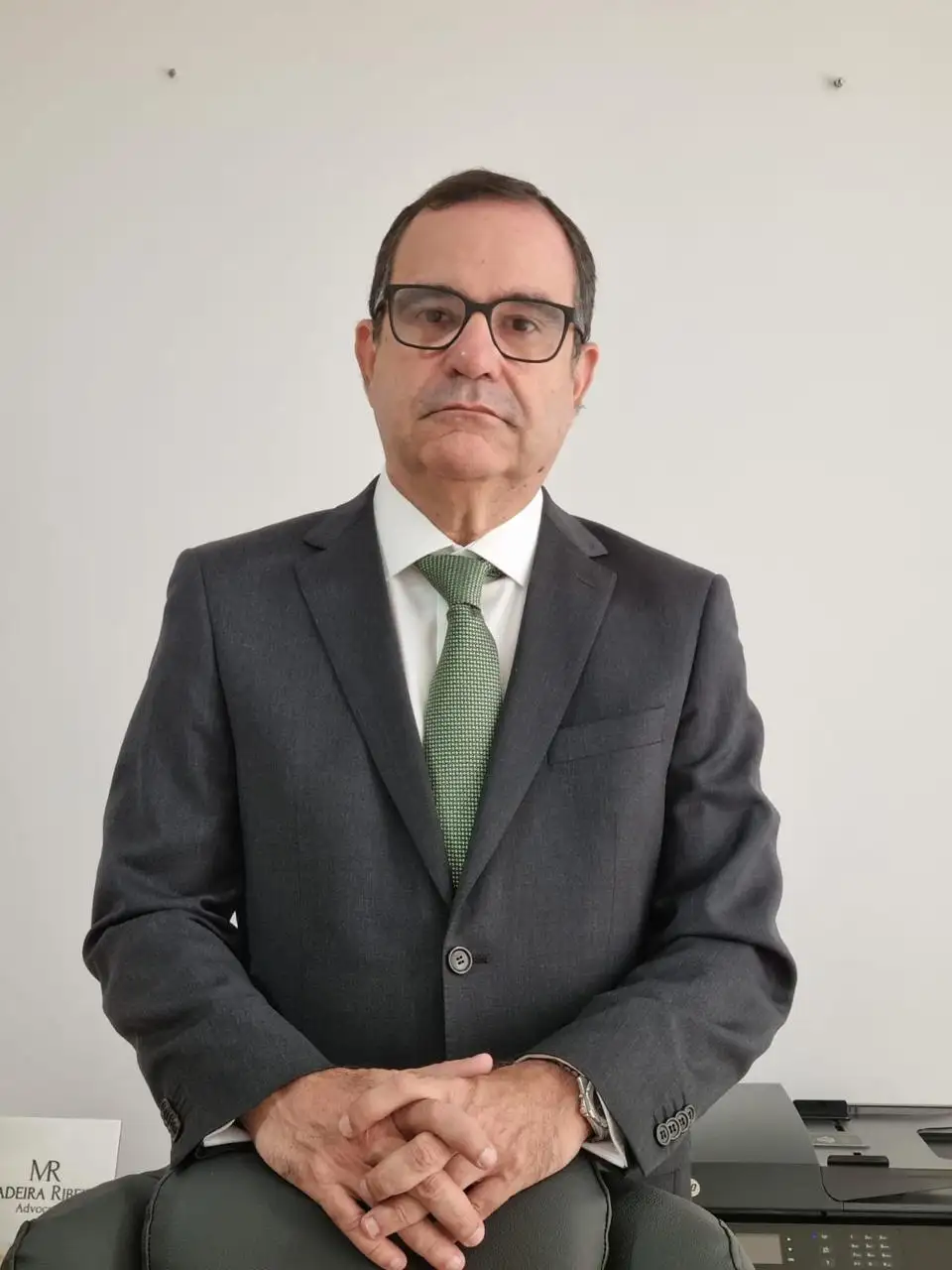 Advogado Edson Madeira Ribeiro em pé no escritório, ao lado da estante de livros jurídicos
